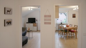 Uma sala de estar moderna com sofá, televisão e área de jantar com mesa e cadeiras.