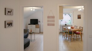 Ett modernt vardagsrum med en soffa, en tv och en matplats med ett bord och stolar.