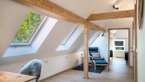 A room with skylights, a wooden ceiling, a blue chair, and a fur chair. - Haus Wiesenruhe Apartment 1 – Modern & Cozy (Seebach)