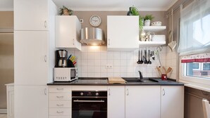 Eine moderne Küche mit weißen Schränken, einer Edelstahl-Dunstabzugshaube, einer Mikrowelle und einem Backofen.
