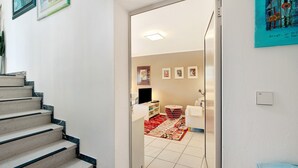 Eine Treppe führt zu einem Zimmer mit einem Bett, einem Nachttisch, einem roten Teppich und einer Wand mit gerahmten Bildern.