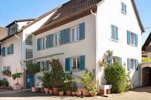 A two-story building with blue shutters, a staircase, and potted plants. - Apartment 'Bluehome Ferienwohnung' with Private Garden and Wi-Fi (Bad Bellingen)