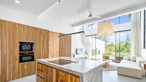 Eine moderne Küche mit Holzelementen, einer großen Kochinsel und Blick ins Freie.