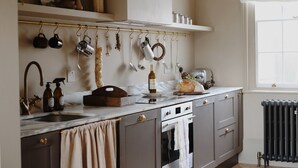 A kitchen with a marble countertop, a hanging pot rack, a radiator, and a window with blinds. - The Nomad House, Ramsgate (Ramsgate)