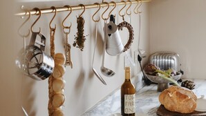 A kitchen with a marble countertop, a bread loaf, a bottle of wine, and various kitchen utensils hanging on a rod. - The Nomad House, Ramsgate (Ramsgate)