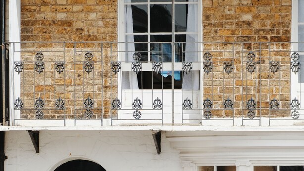 A two-story building with a white facade, a balcony with decorative metal railings, a door with the number 26, and a window with a view of the interior. - The Nomad House, Ramsgate (Ramsgate)