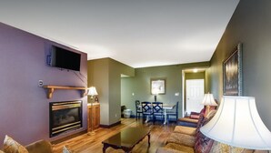 A living room with a fireplace, a television, and a dining area with a table and chairs. - 5 mins to Dollywood - Hideaway Waters 5ppl Condo (Pigeon Forge)