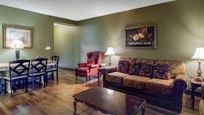 A living room with a wooden coffee table, a red armchair, a patterned sofa, and two lamps. - 5 mins to Dollywood - Hideaway Waters 5ppl Condo (Pigeon Forge)