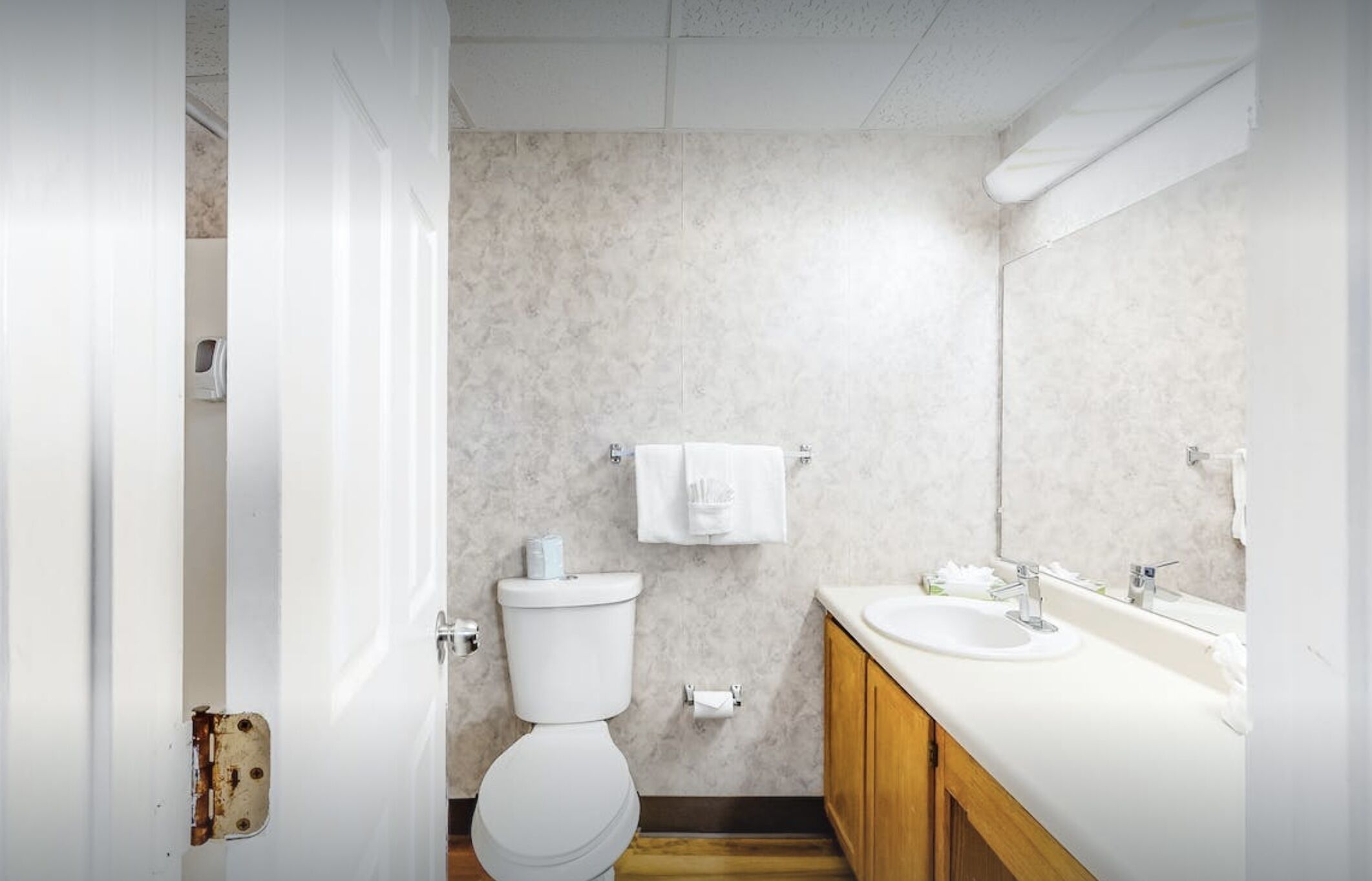 A bathroom with a toilet, sink, and mirror.