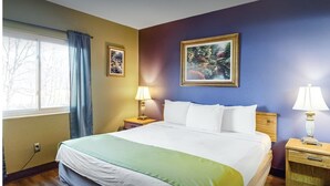 A hotel room with a large bed, two bedside tables with lamps, a window with curtains, and a framed picture on the wall. - 5 mins to Dollywood - Hideaway Waters 5ppl Condo (Pigeon Forge)