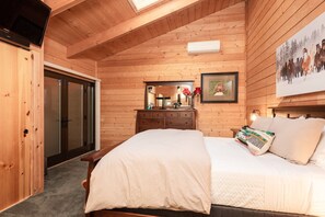 Un dormitorio de cabaña de madera con una cama, un aparador y un cuadro en la pared.