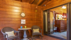 A wooden-paneled room with wicker chairs, a small round table, and a clock on the wall. - Modern Mountain Retreat w/ Amazing Views • Hot Tub • Deck • Pets Welcome (Idyllwild-Pine Cove)