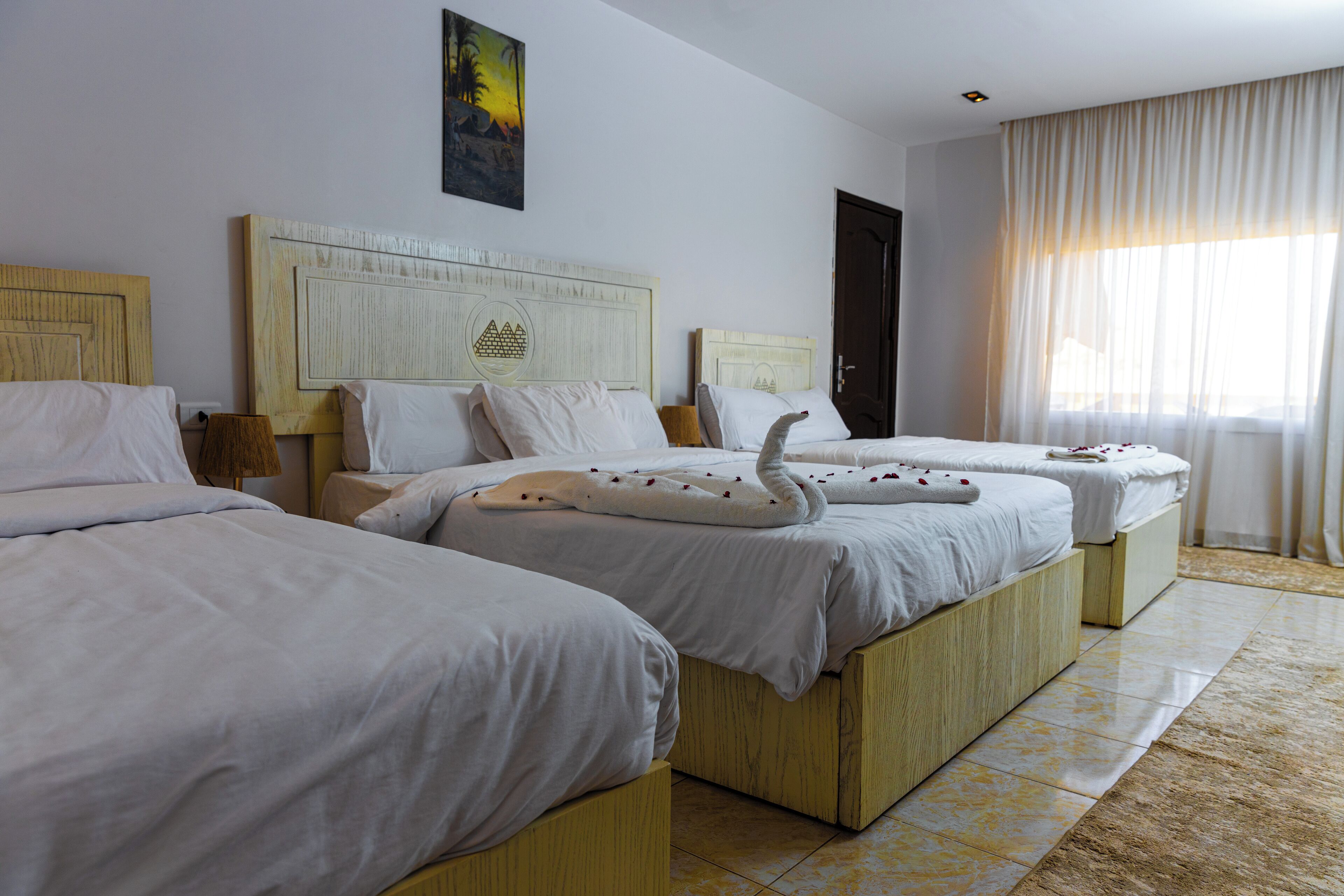 A hotel room with two beds, each with a wooden headboard and white bedding.