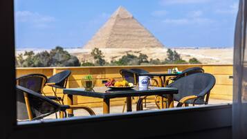 Ein Tisch mit Stühlen und Blick auf die Cheops-Pyramide.