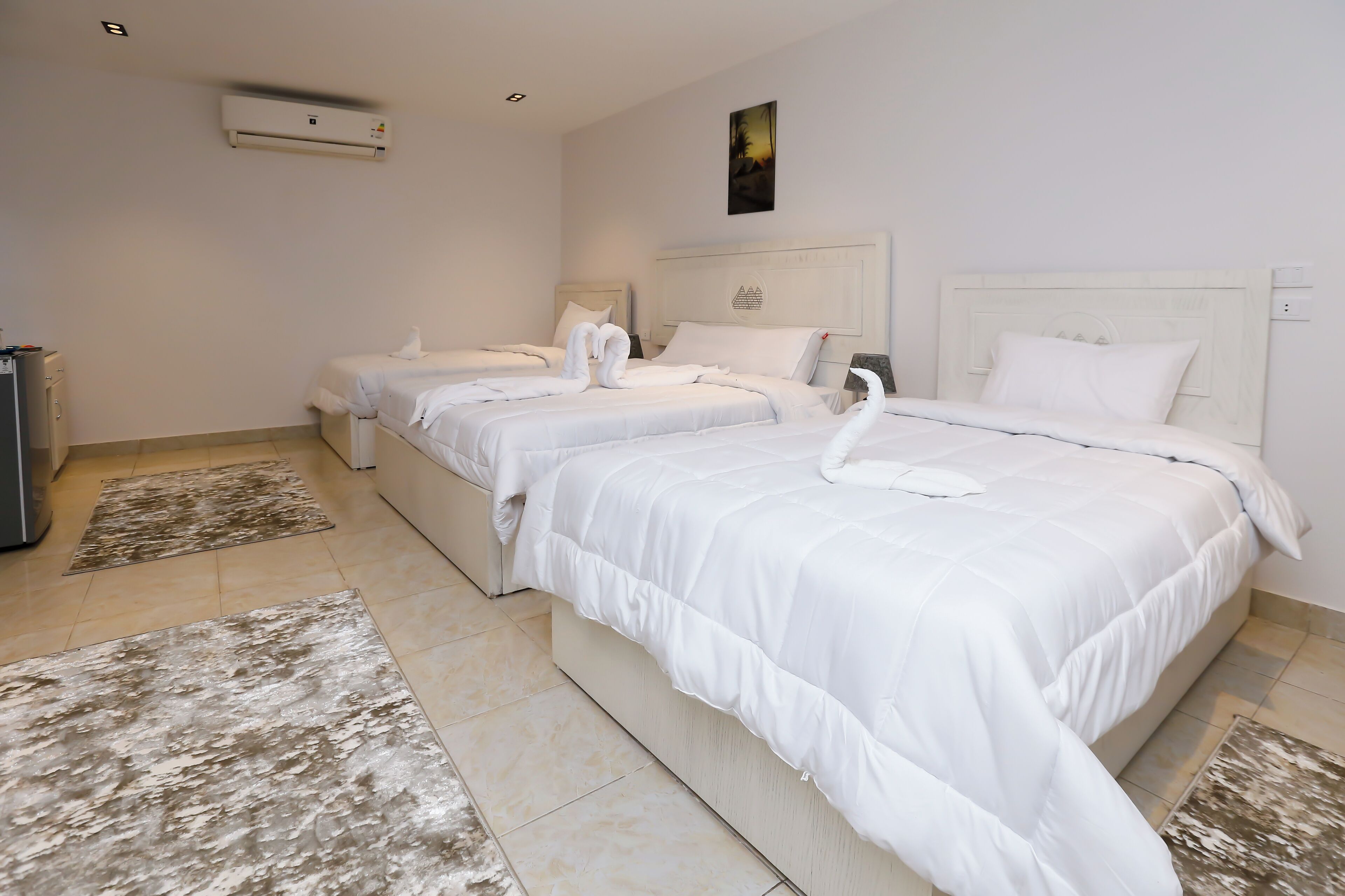 A hotel room with three beds, each with white bedding and decorative swans.