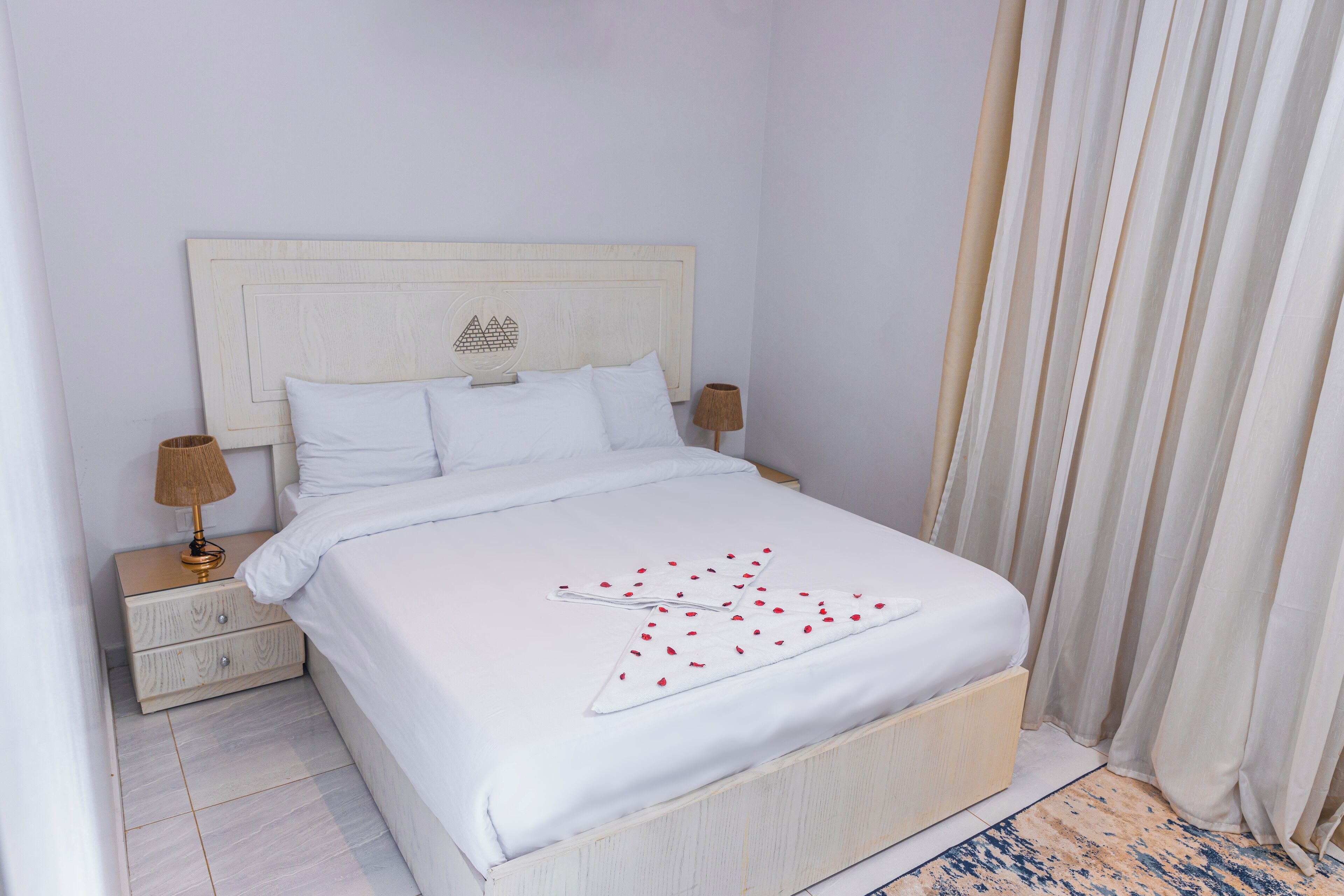 Una cama bien hecha con sábanas blancas y un estampado blanco y rojo decorativo en la colcha.