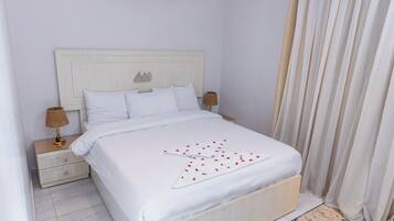 Una cama bien hecha con sábanas blancas y un estampado blanco y rojo decorativo en la colcha.