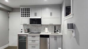 Una cocina compacta con armarios blancos, un microondas negro, lavavajillas y un lavabo con grifo moderno.