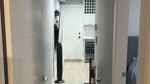 Un pasillo con una puerta blanca a la izquierda, una puerta blanca a la derecha y una rejilla de ventilación en el techo.