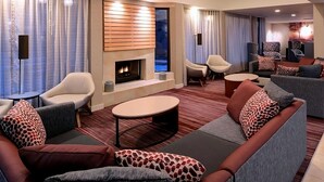 Un'area lounge moderna con divani, poltrone, un caminetto e vista sull'esterno.