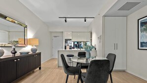 A modern dining area with a glass table, dark chairs, and a dark wooden console.
