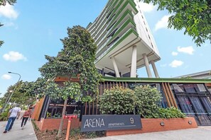 A modern building with a sign reading 'ARENA APARTMENTS 9'.
