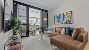 A modern living room with a brown sofa, a coffee table, and a large window.