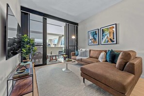 Uma sala de estar moderna com um sofá marrom, uma mesa de centro e uma janela grande.