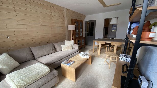 Una sala moderna con pared de madera, un sofá, una mesa de centro y un comedor.