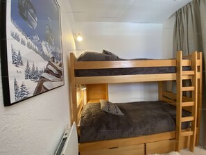 Un letto a castello con una scaletta, un quadro appeso al muro e una finestra con tende.