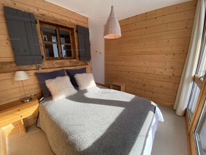 Una camera da letto con un letto, un comodino, una lampada e una finestra con persiane.