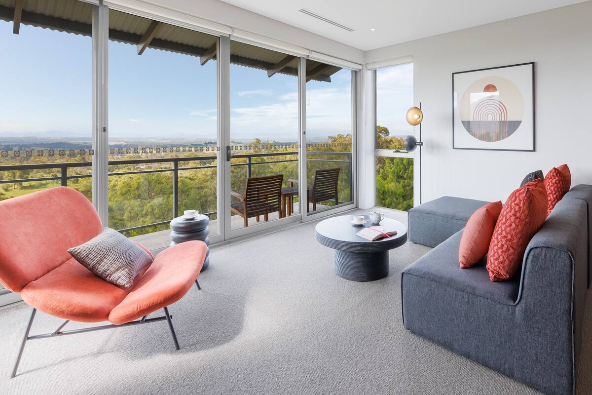 A spacious living area with a large sliding glass door leading to a balcony with a scenic view.