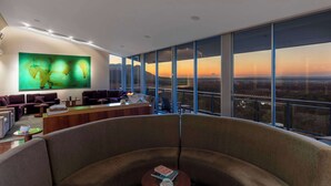 Un moderno vestíbulo de hotel con un amplio ventanal panorámico, una recepción y cómodas zonas de estar.