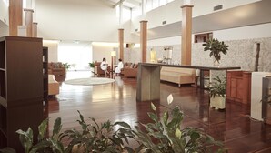 A spacious lobby with a high ceiling, wooden columns, a central seating area, and a kitchen area with a sink and countertop. - Elysia Wellness Retreat (Pokolbin)