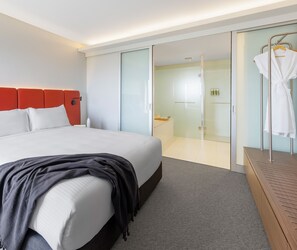 A modern hotel room with a large bed, a walk-in closet, and a glass shower area. - Elysia Wellness Retreat (Pokolbin)