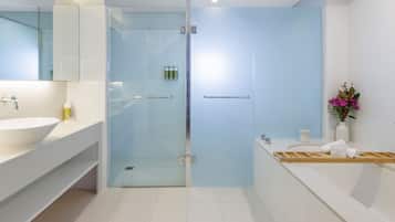 A modern bathroom with a glass-enclosed shower, a white sink, and a vanity with a mirror.
