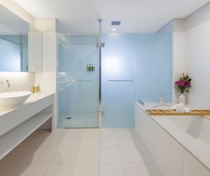 A modern bathroom with a glass-enclosed shower, a white sink, and a vanity with a mirror. - Elysia Wellness Retreat (Pokolbin)