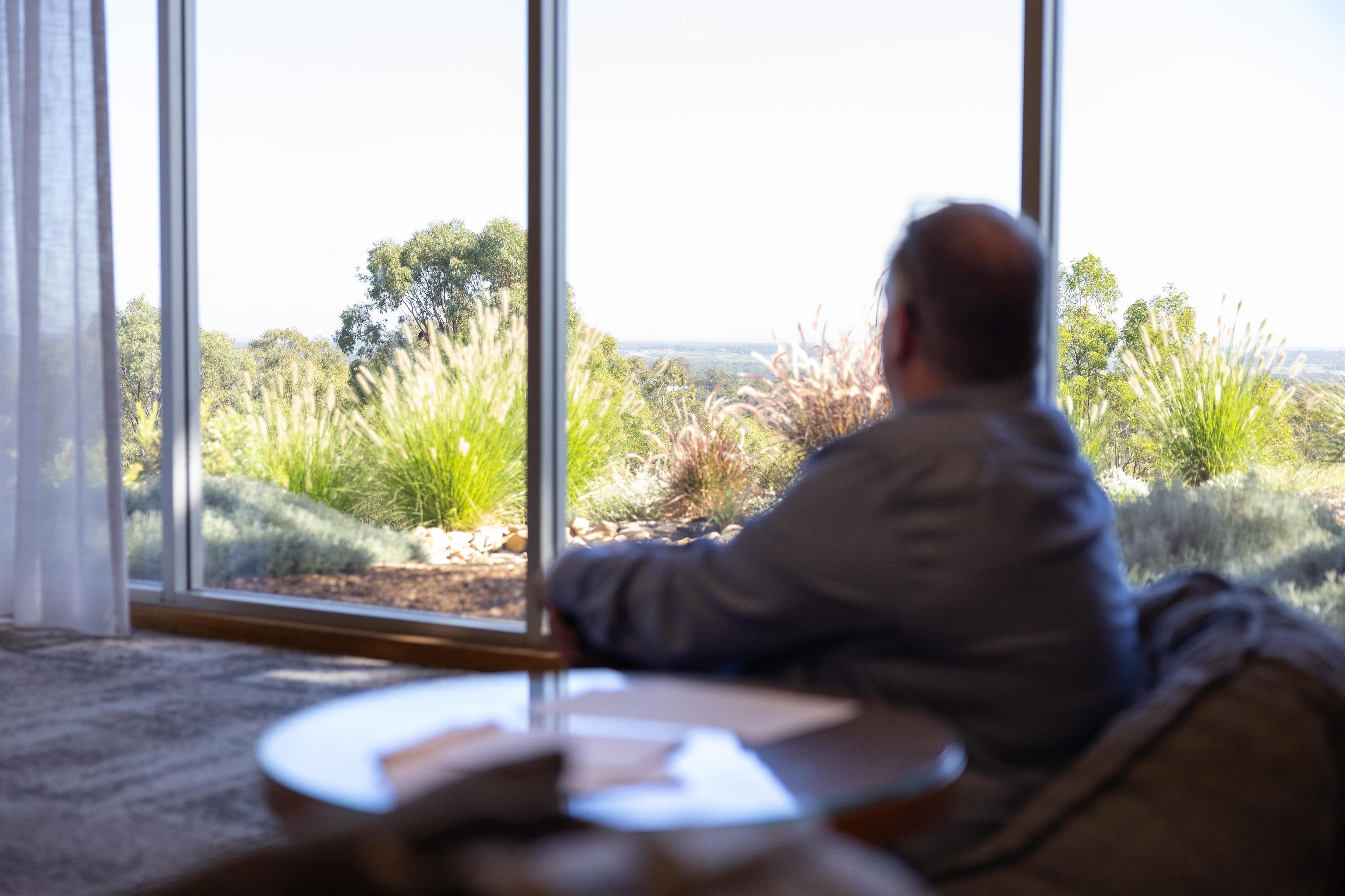 A person sitting by a window with a view of a landscape.