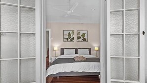 Puerta abierta que da a un dormitorio con una cama, dos lámparas de pared y un ventilador de techo.