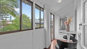 Una habitación con ventanas amplias, techo blanco y una mesa redonda con sillas.