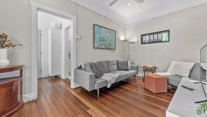 Un salón moderno con un sofá gris, una mesa de centro de madera y una mesita auxiliar blanca.