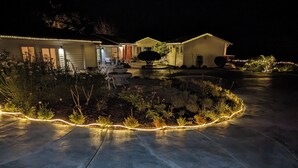 A residential driveway with a concrete path, a landscaped garden with various plants, and a house with a garage. - Sparkling Clean, Private & Quiet! Amazing Ocean Views [1] (Brookings)
