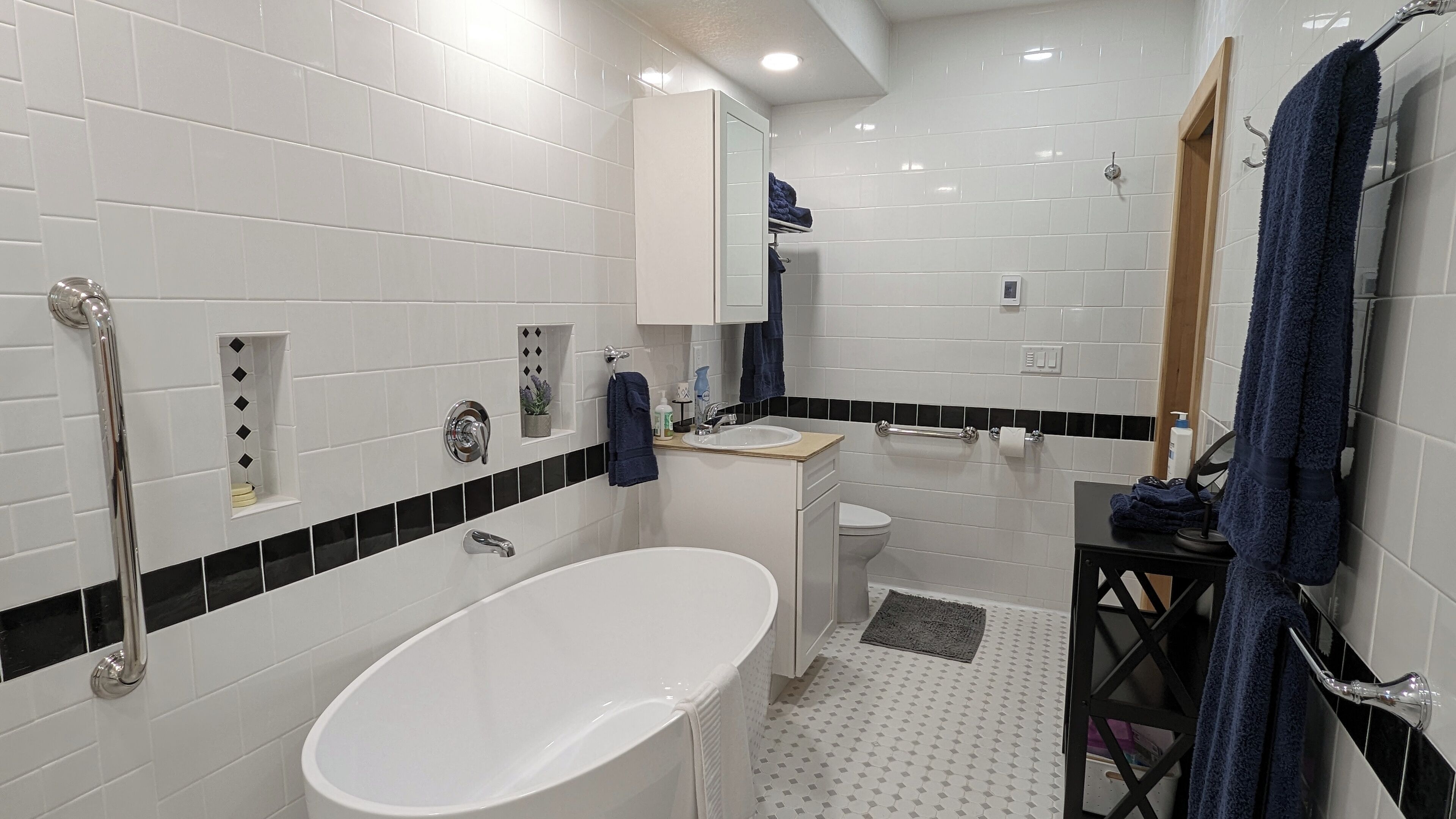 A modern bathroom with a white bathtub, a sink, a toilet, and a shower area.