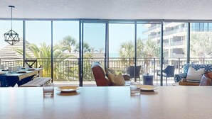 A spacious balcony with a view of palm trees and a building across the water. - Gulf Views From Every Room! Heated Pool. Direct Beach Access.  Recreation Room. Beautiful Beach. (Treasure Island)