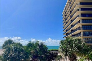 A high-rise hotel with multiple balconies overlooking a beach.