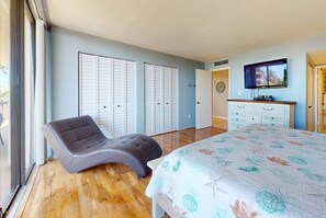 A bedroom with a bed, a chair, a dresser, and a television.