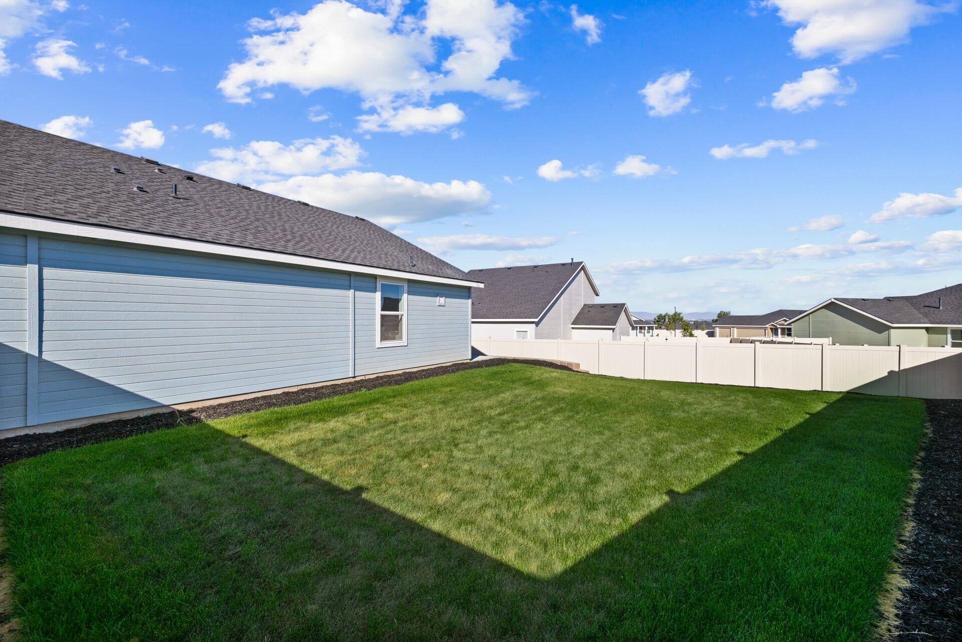 A residential area with houses, a well-maintained lawn, and a clear sky.