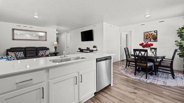 A modern kitchen with white cabinetry, a central island with a sink, and a dining area with a round table and chairs.