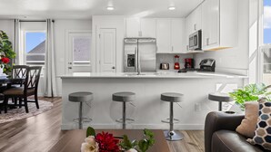 A modern kitchen with white cabinets, stainless steel appliances, and a central island with bar stools.
