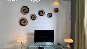Ein Wohnzimmer mit Glastisch, Flachbildfernseher und Wanddekoration.